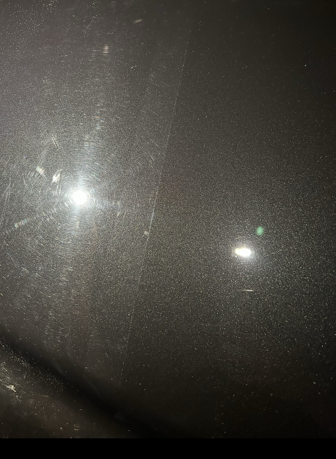 Close-up of swirls and scratches in clear coat under direct light